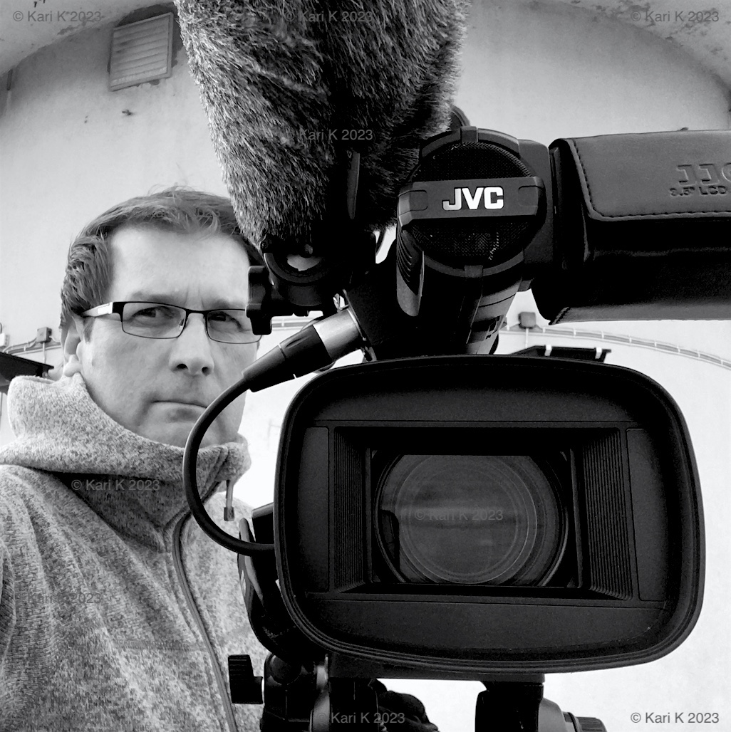 Mustavalkoinen valokuva henkilöstä videokuvaamassa Puijon tornin huipulla.